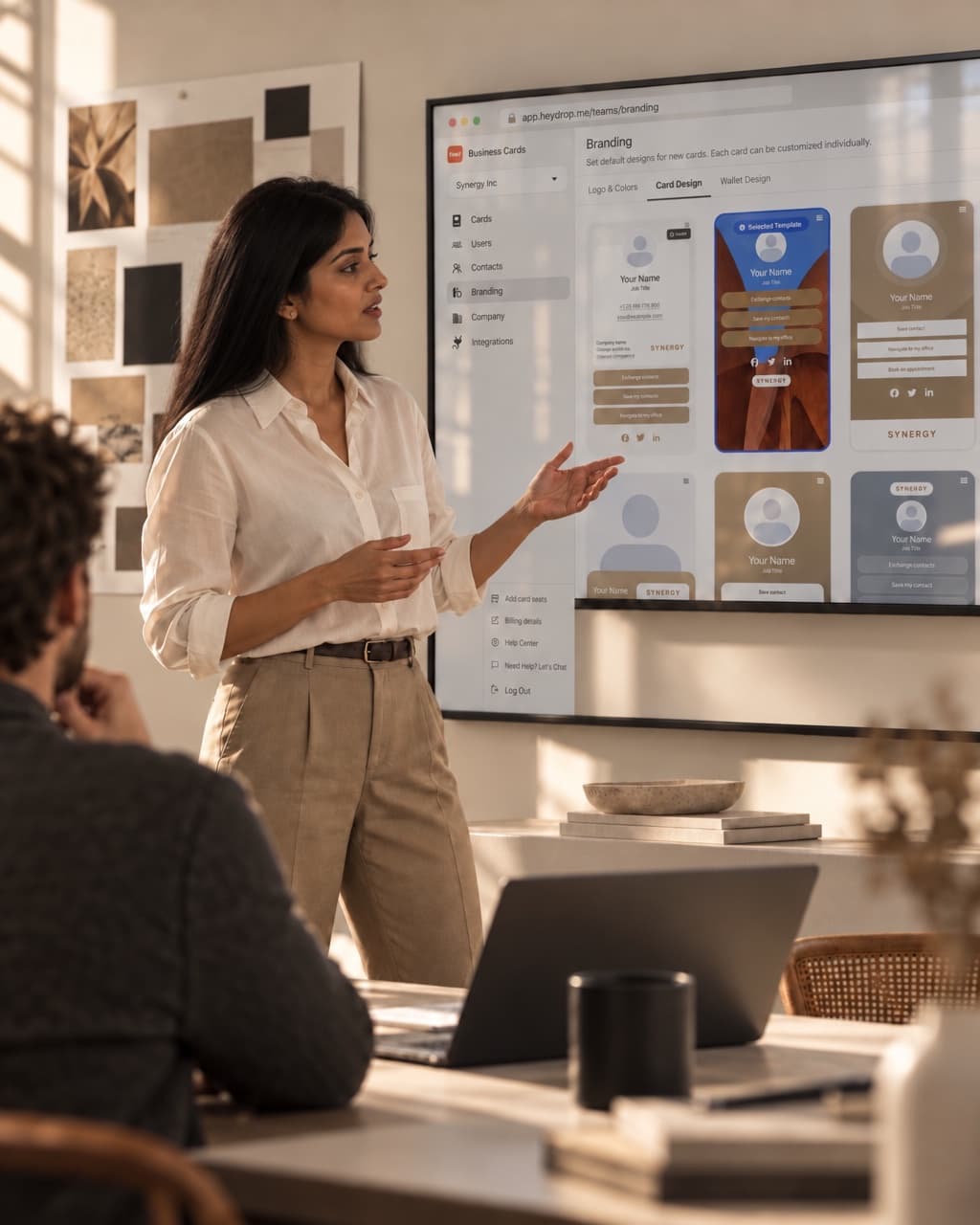 A marketing director presenting branded HeyDrop card designs on a wall screen